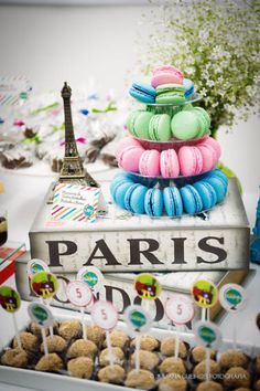 the dessert table is decorated with colorful macaroons and paris themed cupcakes