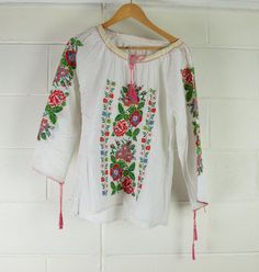 Women's Vintage Indian Blouse | Embroidered | A Condition Description Hungarian style summer blouse featuring embroidered arms and chest. Sleeves and neck fasteners. Great wardrobe staple for Summer. Made in India. Material - Cotton Brand - unbranded  Size -  see measurements   Measurements lying flat Waist - 52cm Bust - 50cm  Length - 66cm  Sleeve Length - 58cm from side neck  This is a vintage item sourced and inspected in Melbourne, Australia. Items have been washed and cared for. Please note Long Sleeve Tops With Floral Embroidery For Summer, Summer Festival Peasant Top With Embroidered Sleeves, Spring Peasant Top With Multicolor Embroidered Neckline, Summer Cotton Top With Embroidered Sleeves, Floral Embroidered Tops For Spring Festival, Folk Style Long Sleeve Top With Embroidered Hem, Summer Folk Peasant Top With Embroidered Sleeves, Summer Casual Peasant Top With Intricate Embroidery, Peasant Tops With Embroidered Sleeves For Summer