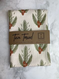 a tea towel with pine cones and berries on it, sitting on a marble surface