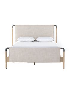 a bed with two pillows on top of it and a wooden frame around the headboard