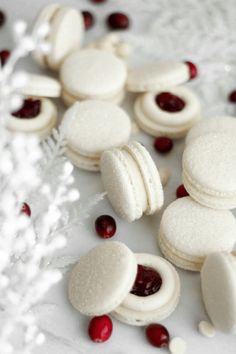 white macaroons and cranberries are scattered on a table with snowflakes