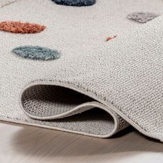 an area rug with various colored dots on it, laying on the floor next to a wooden table