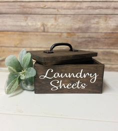 a wooden box with the words laundry sheets on it next to a potted plant