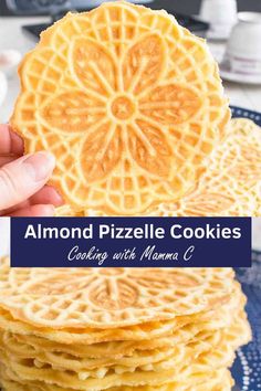 a stack of lemon waffle cookies on a blue plate with the words almond pizzle cookies cooking with mama c