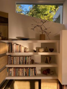 a bookshelf filled with lots of books next to a window in a room