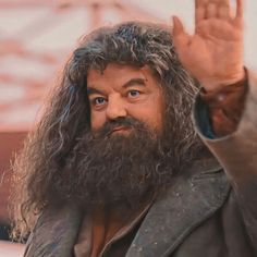 a close up of a person with long hair and a beard holding his hand in the air