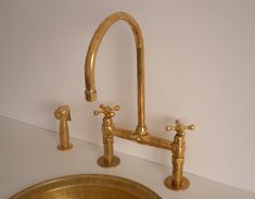 two faucets and a sink in a bathroom with gold fixtures on the counter