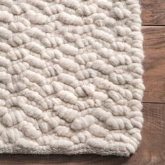 a white rug on top of a wooden floor next to a wood flooring board