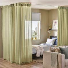 a living room filled with furniture and a large window covered in curtains next to a bed