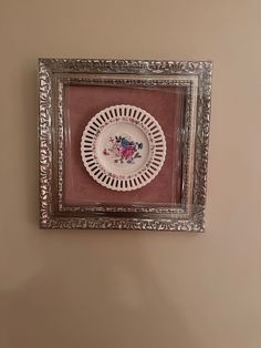 a white plate sitting on top of a wooden table next to a framed wall hanging