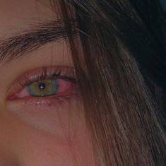 a woman's eye with long hair and green eyes