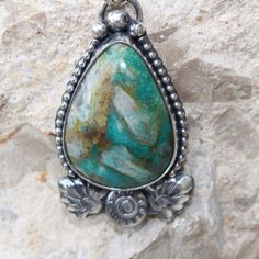 An unusual Chrysocolla teardrop-shaped stone features crystal-like matrics within the stone. The teardrop shape stone is framed with a beaded wire. At the bottom of the pendant, there are handmade Moroccan-style flower and leaf motifs giving this pendant a Moroccan flare. The cool blues and greens of this stone will pair nicely with most of your wardrobe. Teardrop Agate Jewelry For Healing, Healing Teardrop Agate Jewelry, Bohemian Sterling Silver Pendant Drop Necklace, Nature-inspired Teardrop Natural Stones Necklace, Nature-inspired Teardrop Necklace With Natural Stones, Green Drop Bohemian Jewelry, Handmade Bohemian Teardrop Turquoise Necklace, Bohemian Teardrop Healing Jewelry, Bohemian Teardrop Jewelry For Healing