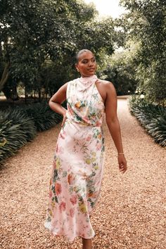 a woman in a floral dress walking down a path