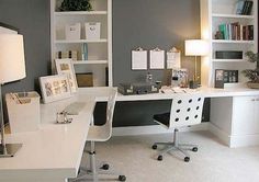 a white desk sitting under a window next to a lamp and bookshelf in a room