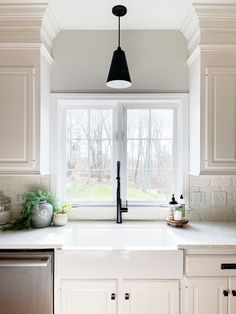 a kitchen with white cabinets and an open window