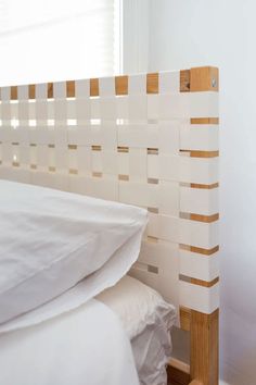 a bed with white sheets and wooden head board