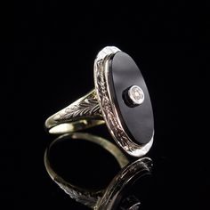 Metal: Solid 14k Yellow and White Gold Stone: 9x18 mm Onyx and a 2mm Diamond Size: 5 Weight: 3.7 grams Era: 1930's This classy ring is white gold on the top and yellow gold on the bottom. Intricately engraved white gold leaves adorn each side of the ring. The oval onyx has a small diamond set in white gold in the center. All of the engraving is still crisp and detailed after all these years. The stone is in very good condition with no eye visible flaws. The interior of the band is stamped with the 14k gold purity stamp. The ring has been professionally cleaned and polished and is ready to wear.  To view our other listings of fine jewelry click here, https://www.etsy.com/shop/seafarevintage?ref=hdr_shop_menu To help make your decision easier, I am always more than happy to take additional p Antique Signet Ring With Polished Finish For Formal Occasions, Classic Formal Engraved Ring With Polished Edges, Classic Black Enamel Signet Ring, Elegant 14k White Gold Signet Ring With Polished Finish, Black Enamel Diamond Anniversary Ring, Elegant Platinum Signet Ring With Polished Finish, Classic White Gold Onyx Rings, Round Black Enamel Diamond Ring For Anniversary, Oval White Gold Jewelry With Black Enamel