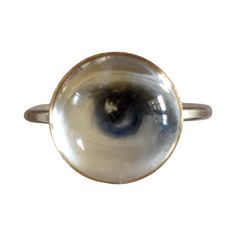 Lover's Eye ring with a round oil painting encased in gold plate over sterling with a quartz crystal cabochon which gives a magical magnifying effect, measuring 1/2"; ring size 5.5. THE HISTORY: Lover's Eyes were a jewelry trend c.1785-1830 of brooches set with tiny watercolor portraits on ivory. Since they were cropped to eyes, they were in many ways more direct and intimate than traditional miniature portraits; but also because they were just eyes, they were often used as daring public testimo Mystical Round Cabochon Jewelry, Brass Dome Ring For Anniversary, Gold Moonstone Ring Collectible, Gold Cabochon Dome Ring, Gold Moonstone Cabochon Ring, Spiritual Yellow Gold Round Crystal Ring, Gold Dome Ring With Cabochon, Brass Moonstone Ring, Round Brass Moonstone Ring