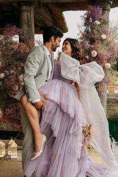 a man and woman standing next to each other in front of some flowers on the ground