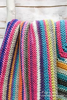 a multicolored crocheted blanket sitting on top of a white wooden chair