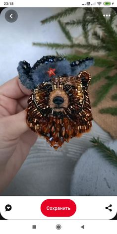 someone is holding up a brooch with a bear on it's head and beads