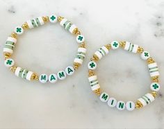 two green and white bracelets with gold beads on top of a marble countertop