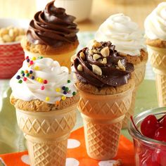 four ice cream cones with chocolate frosting, sprinkles and nuts on top