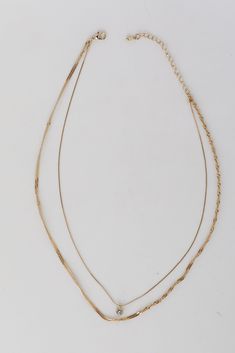 Make sure to add the Lola Gold Layered Chain Necklace to your jewelry box! This trendy necklace features two layers of gold chains with a rhinestone charm. Style the Lola Necklace with any outfit to instantly upgrade your look! Gold Plated Layered Rhinestone Charm Lobster Clasp with Extender Layer 1 | Length 8" Layer 2 | Length 7" Extender | Length 3" Dainty Multi-strand Layered Necklace With Figaro Chain, Double Strand Layered Necklace With Figaro Chain, Double Strand Metal Necklace With Delicate Chain, Trendy Gold Snake Chain Layered Necklace, Dainty Gold Layered Charm Necklaces, Dainty Gold Multi-strand Layered Necklace, Gold Layered Charm Necklace Choker, Gold-tone Multi-strand Layered Necklace, Dainty Metal Layered Necklace With Double Chain