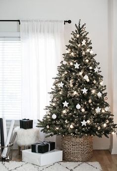 a decorated christmas tree in a living room with white lights and presents on the floor