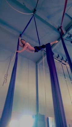 a woman is performing aerial acrobatics in a tent