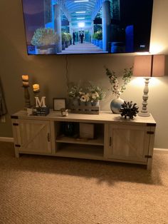 a flat screen tv mounted to the side of a wall next to a table with vases on it