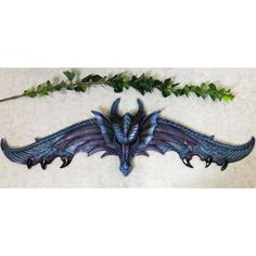 a blue dragon head hanging from the side of a wall next to green vines and ivy