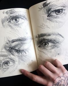 a person's hand holding an open book with drawings on the inside of it