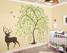 a baby's room with a tree and deer wall decals on the walls