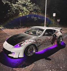 a white sports car with purple lights on it