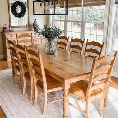 a dining room table and chairs in front of a window with wreaths on it