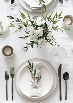 the table is set with black and white plates, silverware, and flower centerpieces