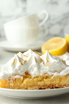 a piece of lemon meringue pie on a plate next to some lemons