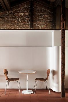 two chairs and a table in a room with exposed brickwork on the wall behind them