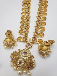 "Handmade Indian Jewelry, best to wear for traditional ceremonies or Indian wedding. This bridal jewelry has an ethnic finish. It has Cubic Zircon stones with semi-precious rubies. It is a Bollywood style one gram jewelry. Handmade Indian Jewelry item * Necklace Set is a combo of Necklace & jumka Earrings * Necklace is adjustable with adjustable back chain/ Dori/ Cord * Earring Length: 2\" , Earring Width: 1.25\" * Necklace length; 32\" approx * Gold Color is a gold-tone which has a beautifu Gold Temple Necklace With Stones For Wedding, Long Necklace Jewelry For Puja And Diwali, Festive Hand Set Round Temple Necklace, Festive Round Temple Necklace With Hand Set, Gold Wedding Temple Necklace With Stones, Diwali Puja Long Necklace Jewelry, Kundan Long Necklace Temple Jewelry, Gold Bollywood Bridal Necklace With Stone Setting, Bollywood Style Gold Bridal Necklace With Stone Setting