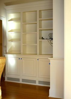 an empty room with white bookcases and wood flooring on the side wall