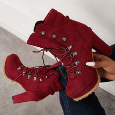 a woman is holding her red boots in one hand and the other with silver studs on them