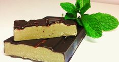 two pieces of chocolate and mint on a white surface with a green sprig