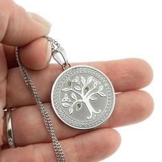 Celebrate the beauty and meaning of the Celtic Tree of Life with this exquisite stainless steel pendant necklace. The intricate Tree of Life design is reverse sandblasted into a substantial 1-inch round pendant, accented with trinity knots and three genuine light emerald stones for a pop of color and Irish flair. The 18-inch chain with 3-inch extender allows you to adjust the length for a perfect fit. The Tree of Life is a powerful symbol in Celtic culture, representing the interconnectedness of Engraved Stainless Steel Medallion Jewelry, Symbolic Silver Necklace With Laser Engraving, Symbolic Silver Jewelry With Laser Engraving, Symbolic Silver Laser Engraved Jewelry, Silver Stainless Steel Jewelry With Engraving Option, Symbolic Laser Engraved Silver Jewelry, Round Stainless Steel Jewelry With Engraving Option, Silver Metal Jewelry With Engraving Option, Nickel Free Stainless Steel Necklace For Anniversary