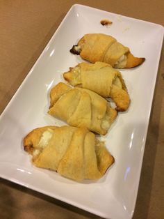 three pastries on a white plate sitting on a table