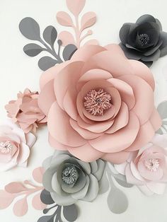 paper flowers are arranged on a white surface with grey and pink leaves around the edges