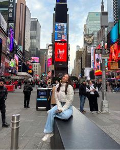 a woman sitting on top of a bench in the middle of a city