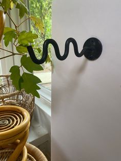 a black snake on the side of a white refrigerator next to a potted plant