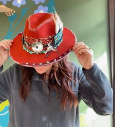 Such a fun hat- burnt orange color, polyester fabric, western style accents, beads and turquoise pops. Toped off with scrap bandana and turquoise chunk pieces around the rim. Accented with silver distressing  one size fits most. Red Western Fedora For Kentucky Derby, Red Western-style Fedora For Western-themed Events, Western Style Felt Hat For Winter Festivals, Western Style Winter Festival Felt Hat, Red Western Hat For Fall, Red Adjustable Hat For Western-themed Events, Adjustable Red Felt Hat For Western-themed Events, Red Hats For Rodeo And Kentucky Derby, Western Style Costume Hats For Rodeo