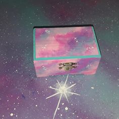 a pink and blue box sitting on top of a purple surface with stars in the sky